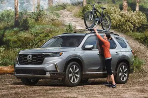 A person placing their bike on the roof rack of a 2024 Honda Pilot near Indianapolis, Indiana