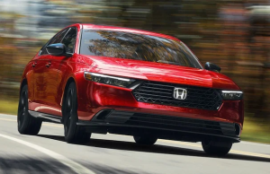 A red 2024 Honda Accord Hybrid driving down a wooded road near Indianapolis, Indiana