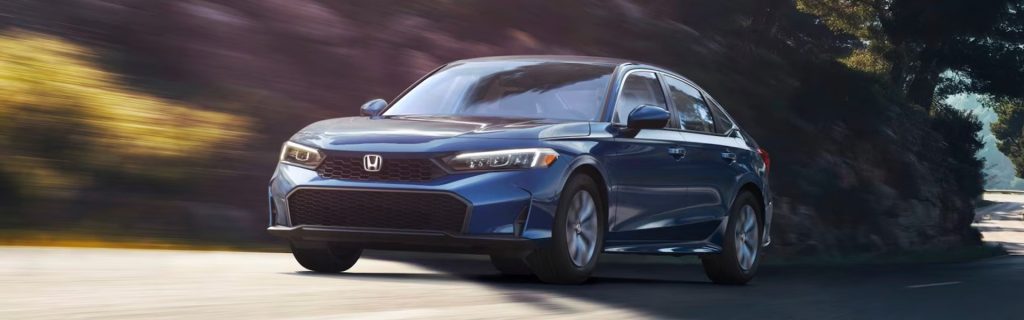 A blue Honda sedan driving on a scenic road.