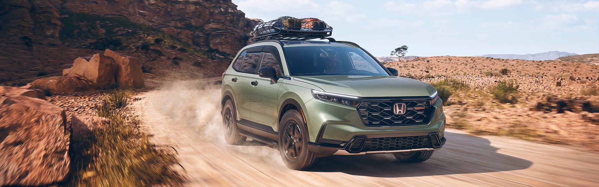 Honda SUV driving through a rugged desert landscape with roof cargo carrier.
