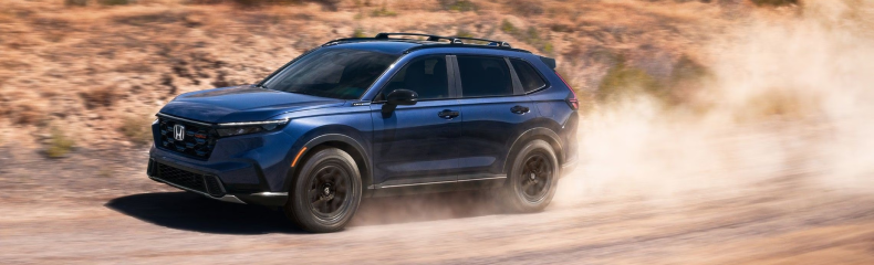 Blue Honda CR-V TrailSport kicking up dust on a desert dirt road
