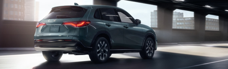 Dark green Honda HR-V seen from the rear quarter driving through a sunlit parking structure