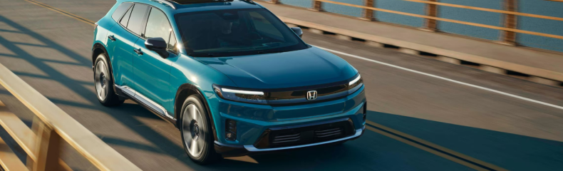 Teal Honda Prologue electric SUV driving across a bridge