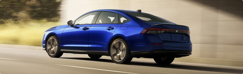 Blue Honda sedan driving along a highway, seen from the rear quarter