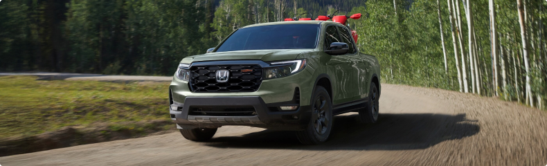 Green Honda Ridgeline TrailSport driving down a gravel road through an aspen forest