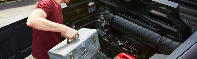 Man lifting a toolbox out of the open In-Bed Trunk of a Honda Ridgeline